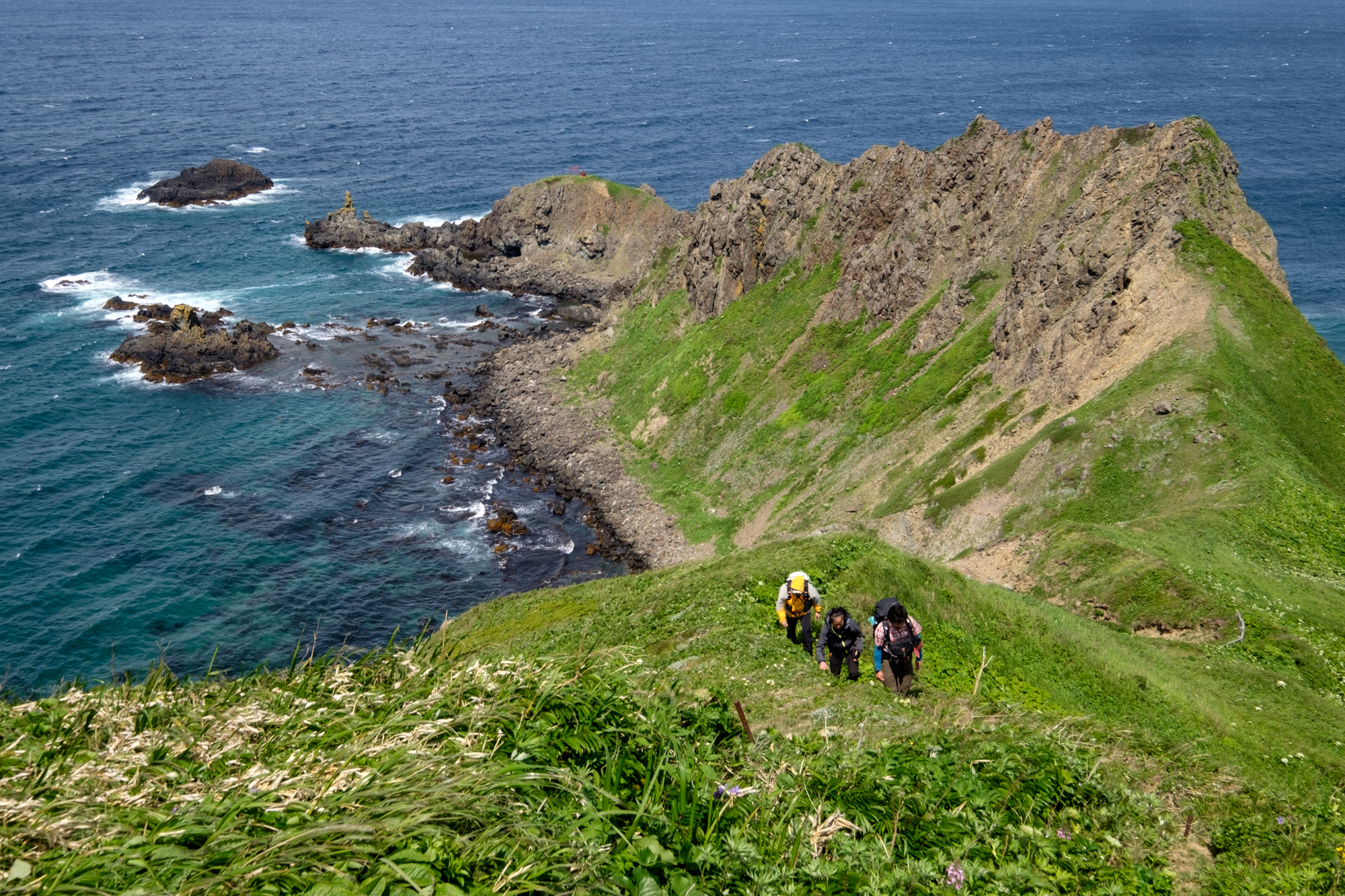 Hikers climbing a rugged headland on Rebun Island