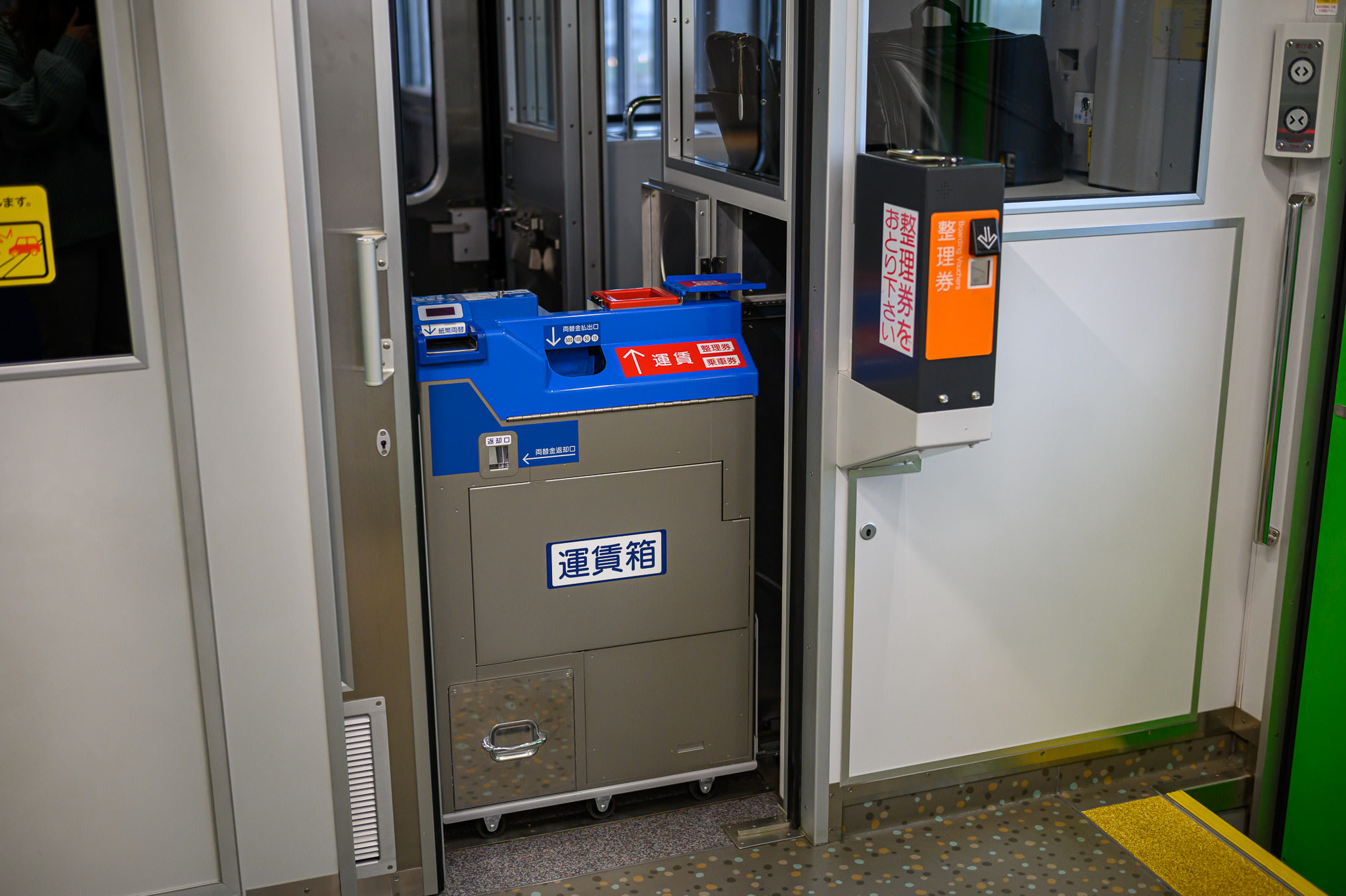 A ticket dispenser and a fare box on a small local train in Hokkaido. There is no electronic pad for an IC Card on either device.