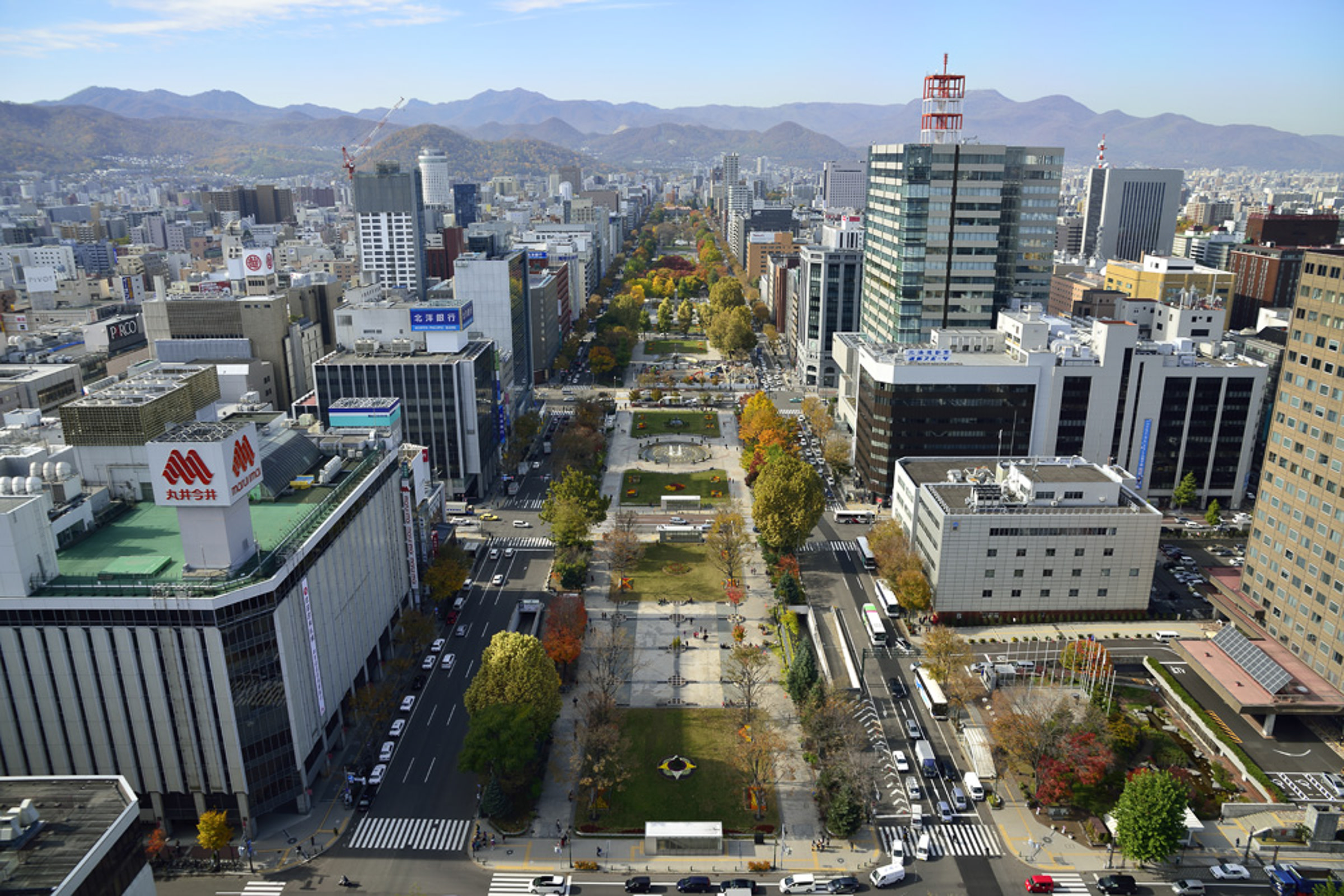 An aerial view of Odori Park in Sapporo. The park stretches out across the middle of a large city, flanked by skyscrapers.