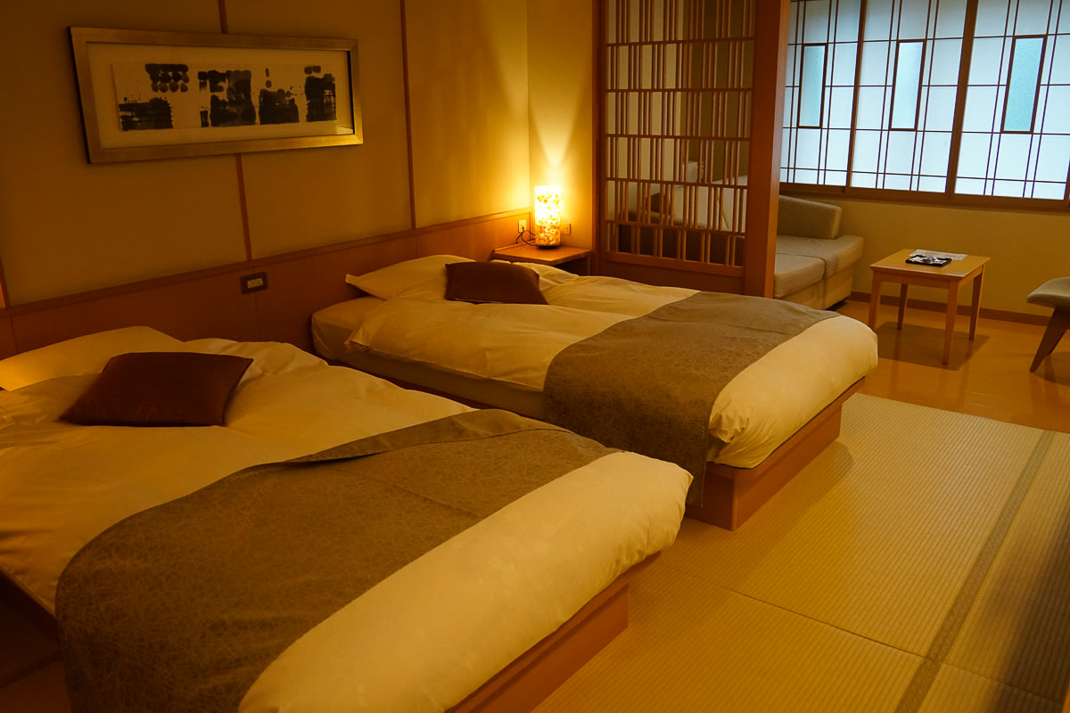 Two single beds sit on a tatami floor in a Japanese style bedroom.