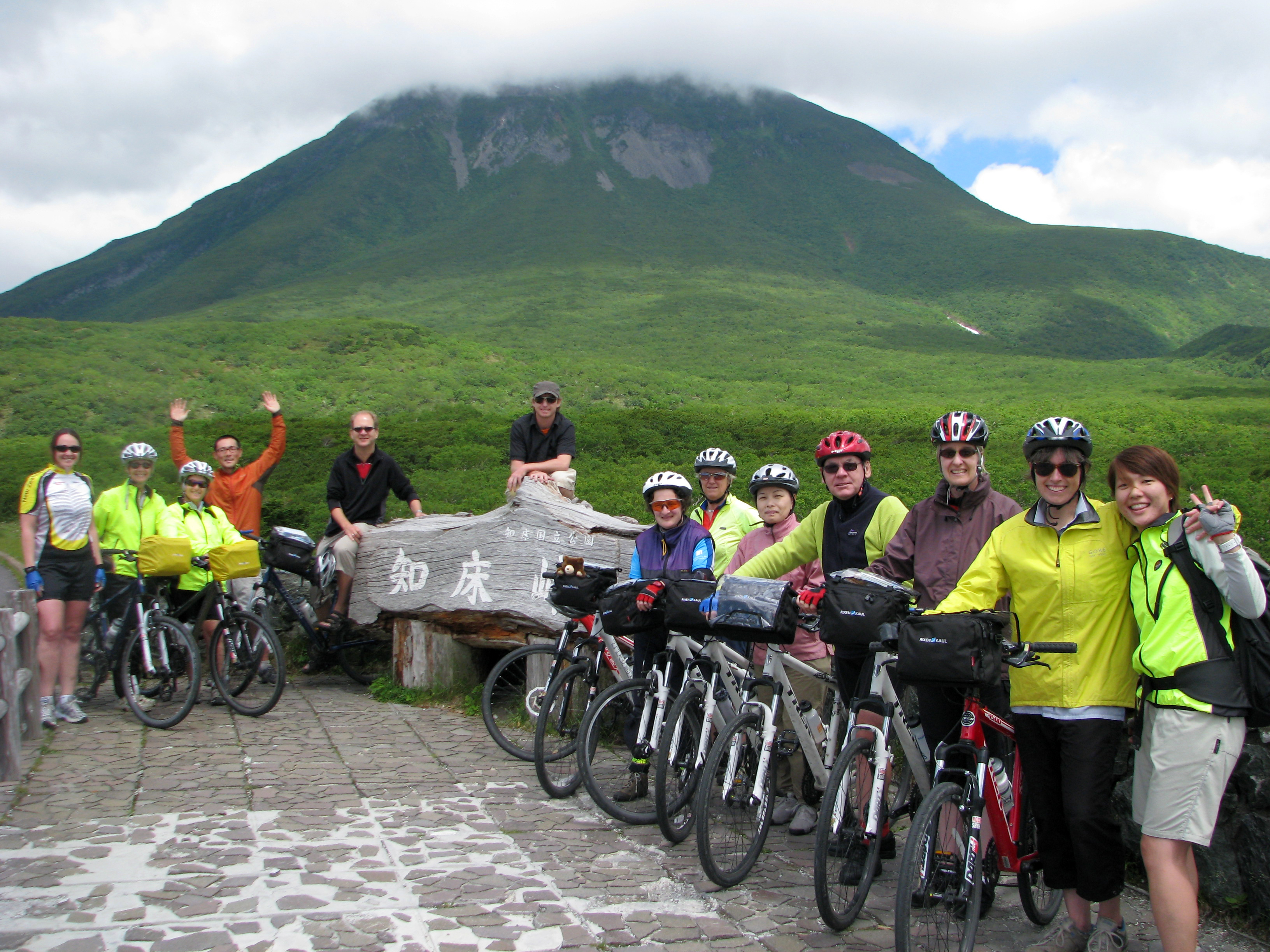 A group of happy cyclists pose at the base of Mt. Rausu