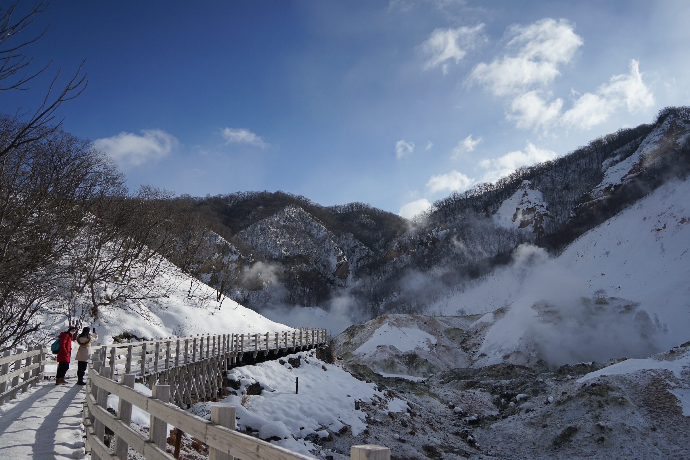 Visitors walking on the boardwalk at Noboribetsu Jigokudani in winter.