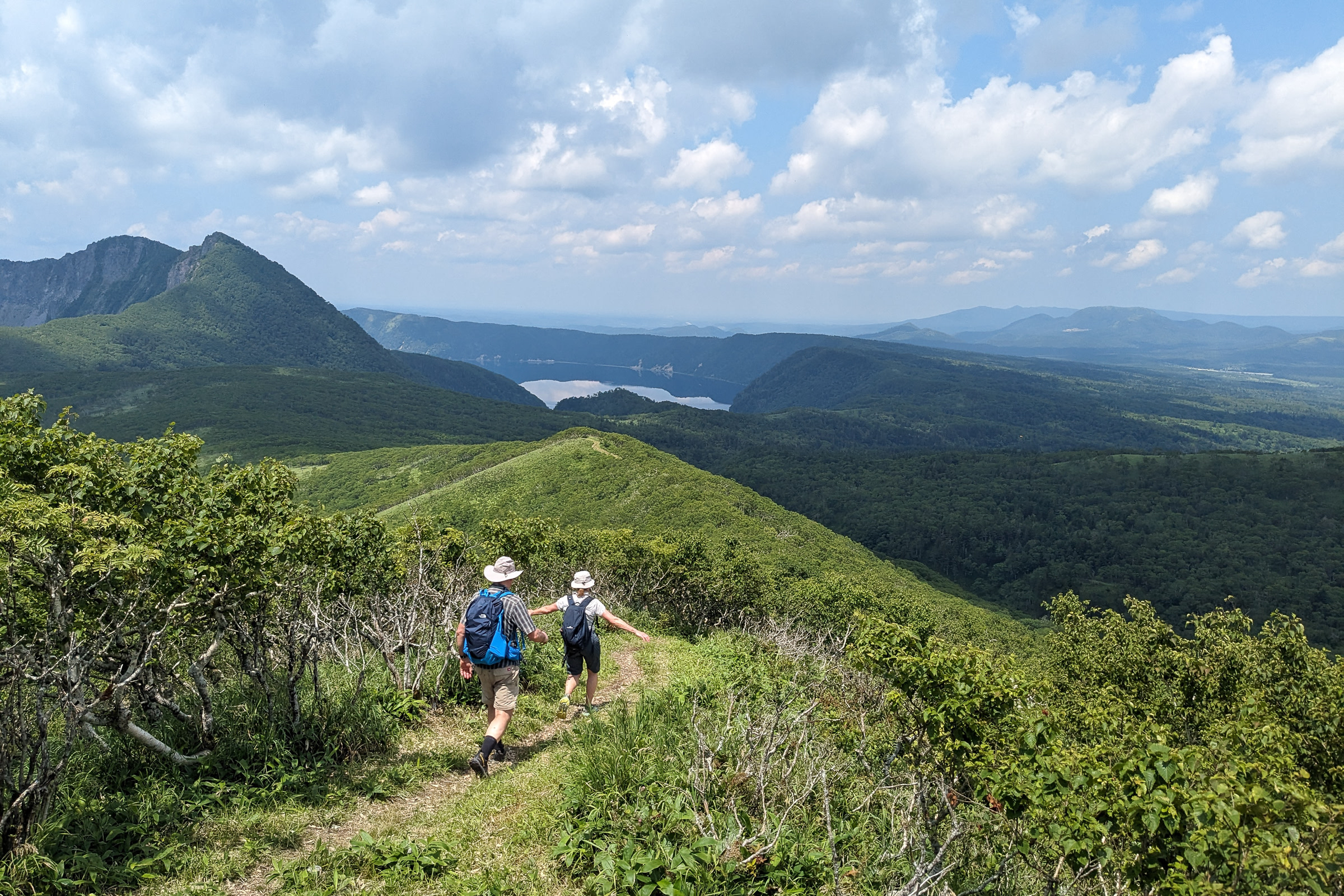 Hikers enjoy the view and weather as they head towards Mt. Mashu during their Lake Mashu traverse hike. 