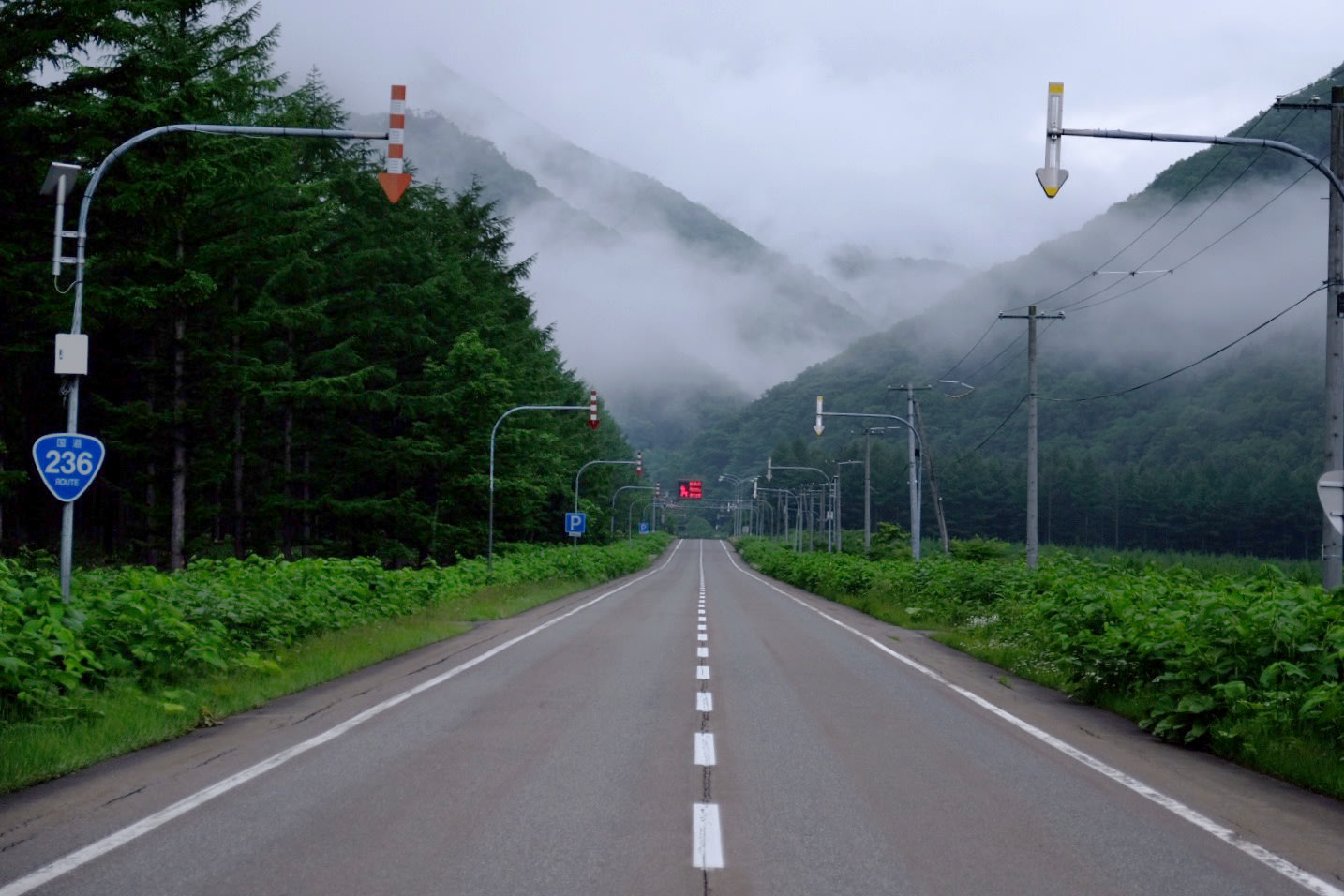 An empty road leads away towards Hokkaido's Hidaka mountains shrouded in mist.