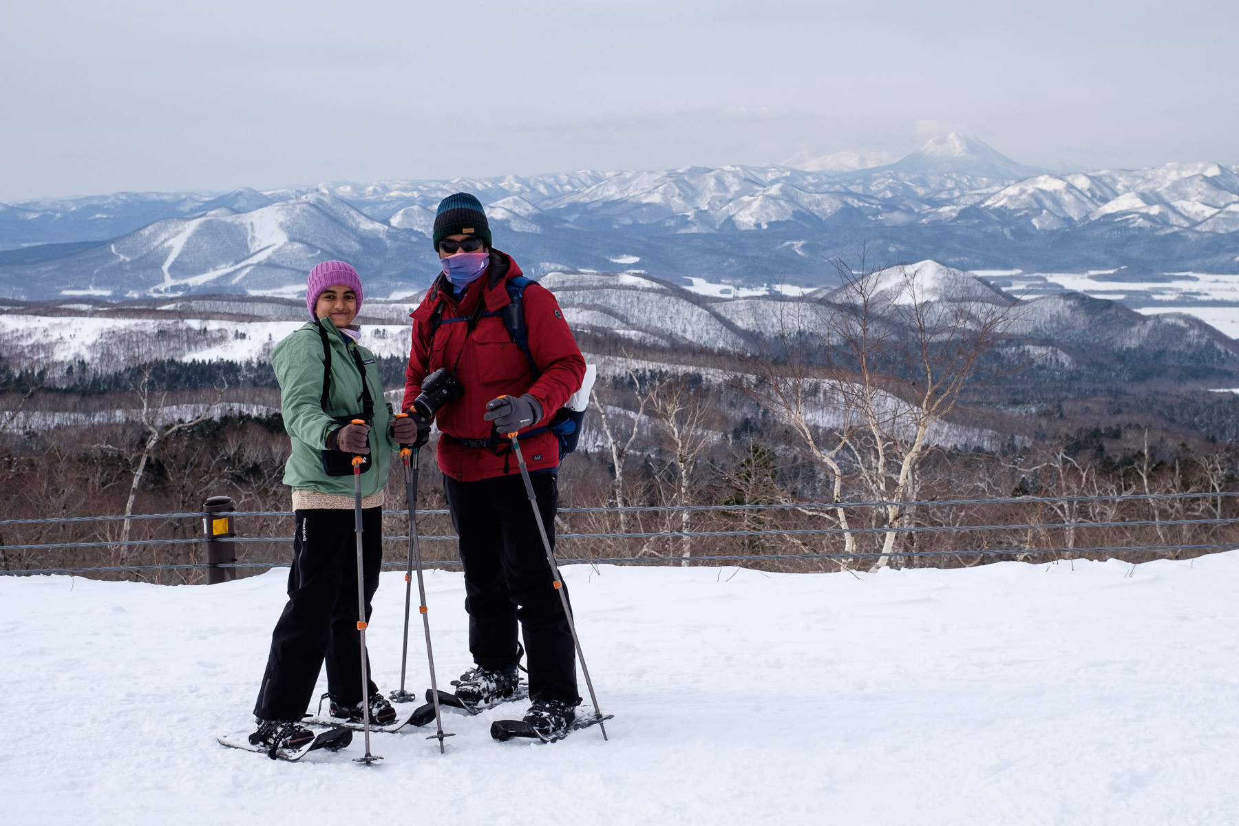 Two snowshoers pose for a photo with Mt Oakan in the background