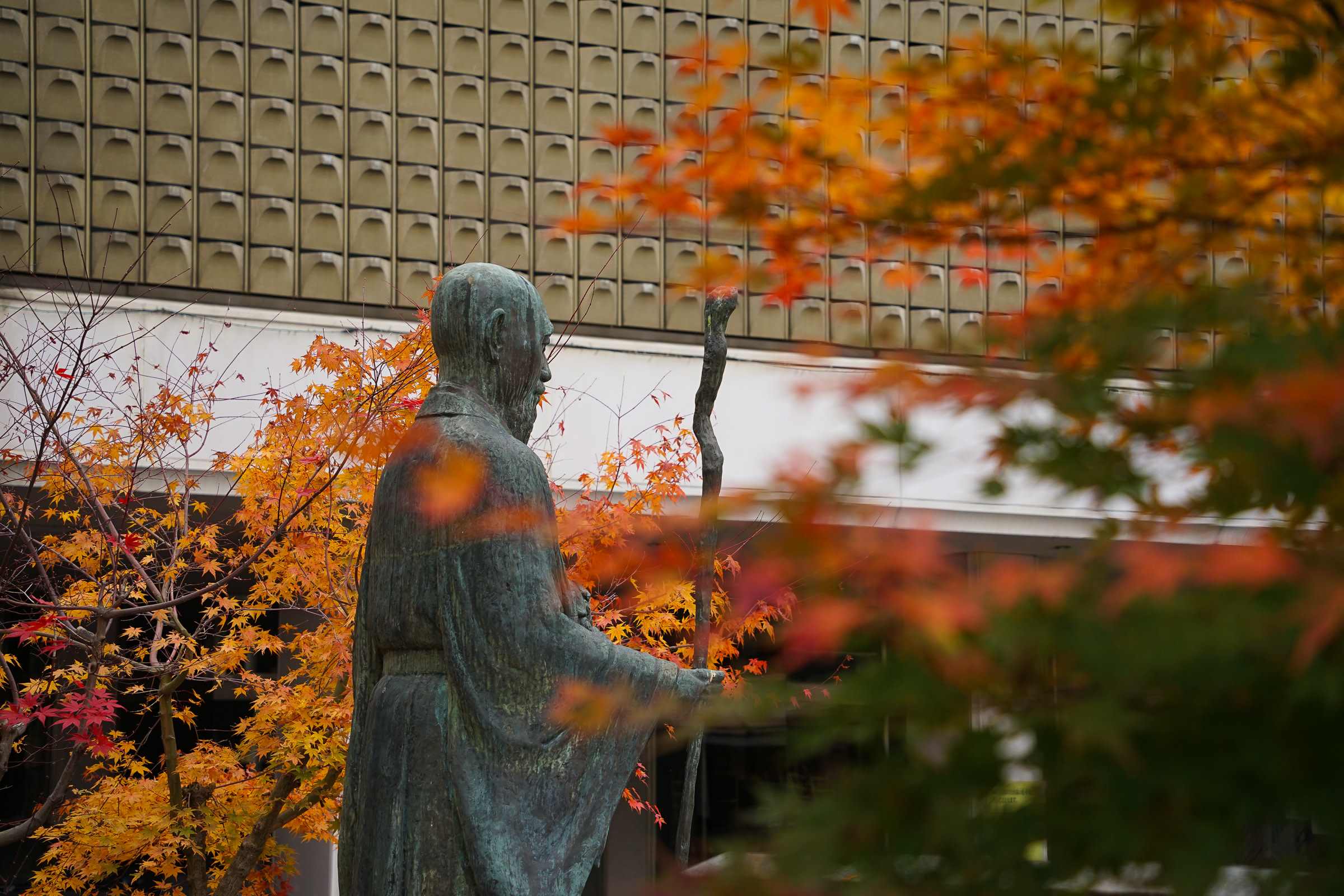 A statue of the Buddhist monk Jozan is offset by beautiful orange leaves.