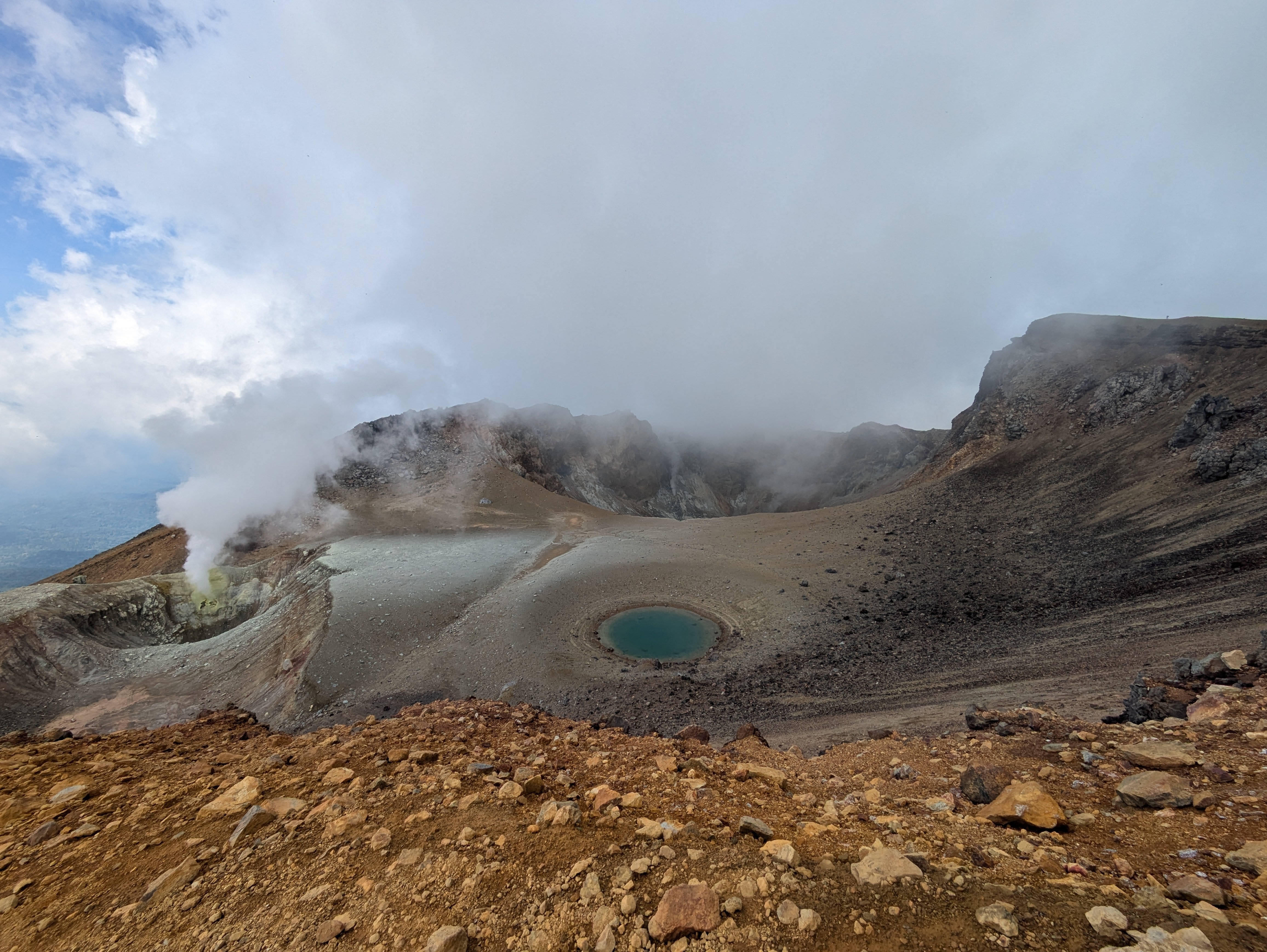 Volcanic ponds and craters at the summit of Mt. Meakan in Hokkaido. The scenery is very rocky and steam is rising from one of the craters.