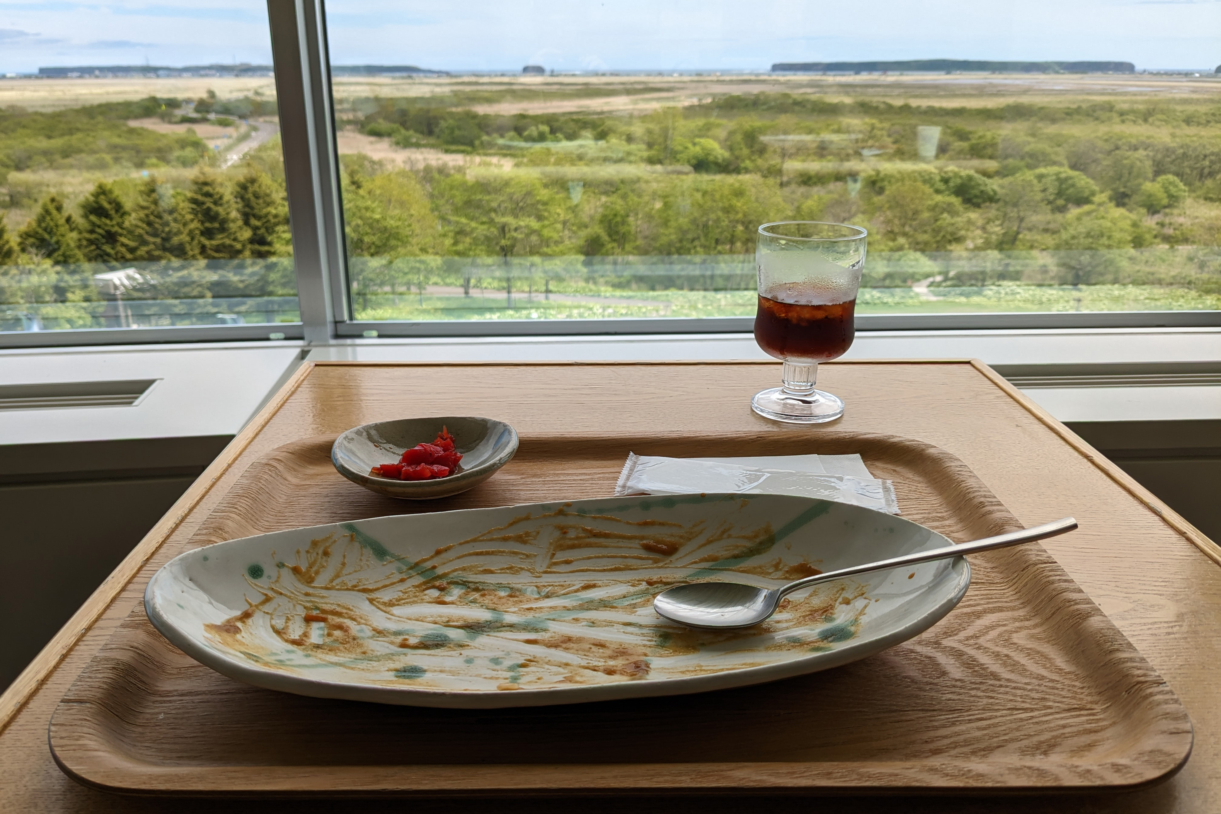 An empty plate of curry sits on a table overlooking the Kiritappu wetlands