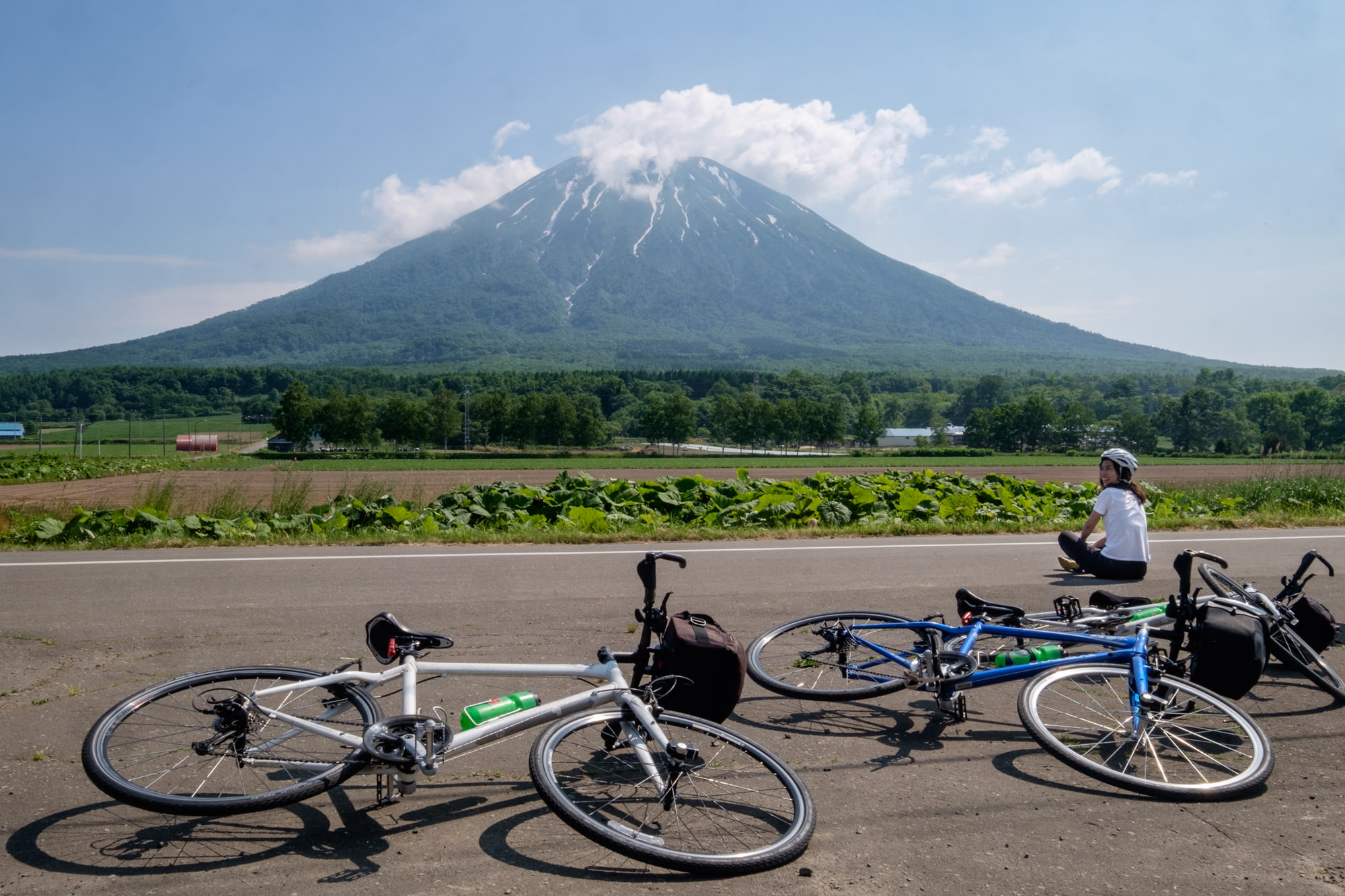 A cyclist takes a break in front of Mount Yotei whilst on a cycling tour.
