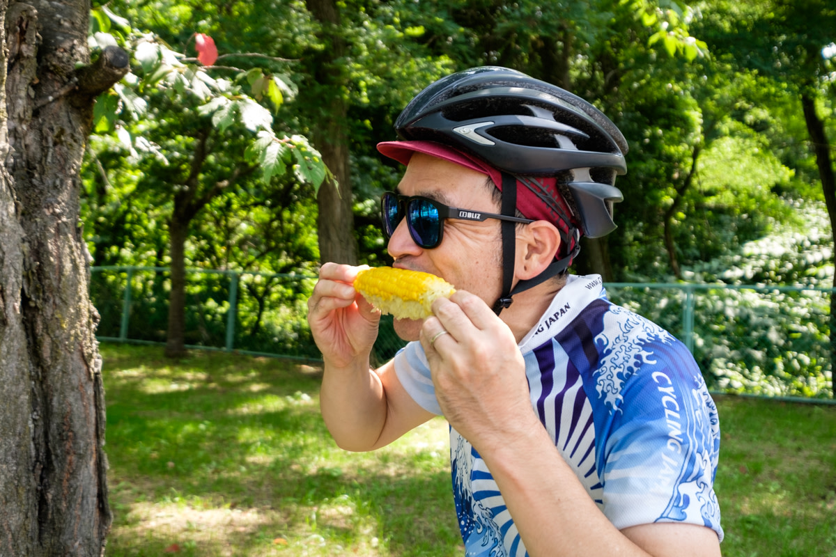A cycling guide eats sweetcorn from the kob