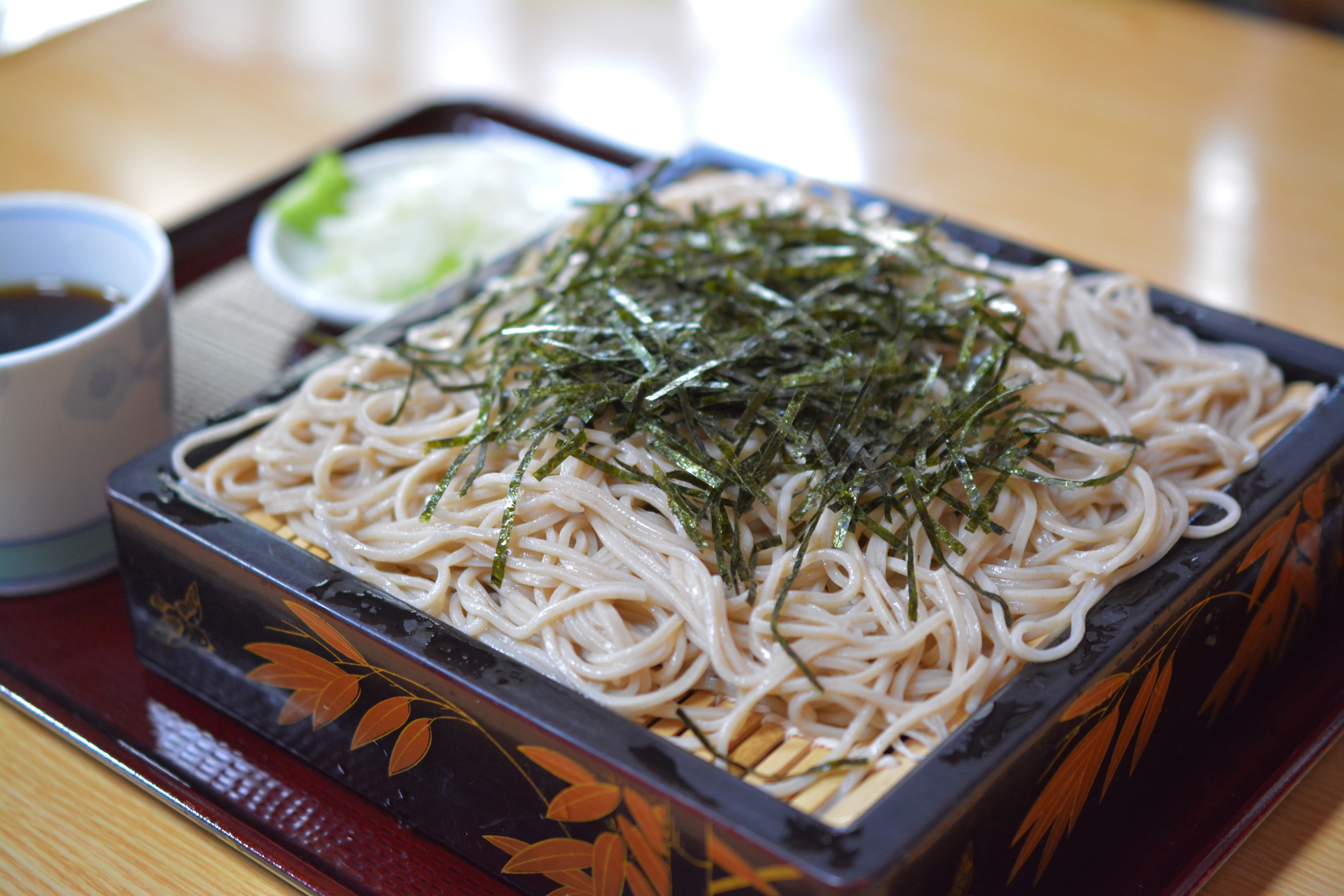 A box of zaru-soba, cold soba noodles. They are in a square box and topped with plenty of seaweed.
