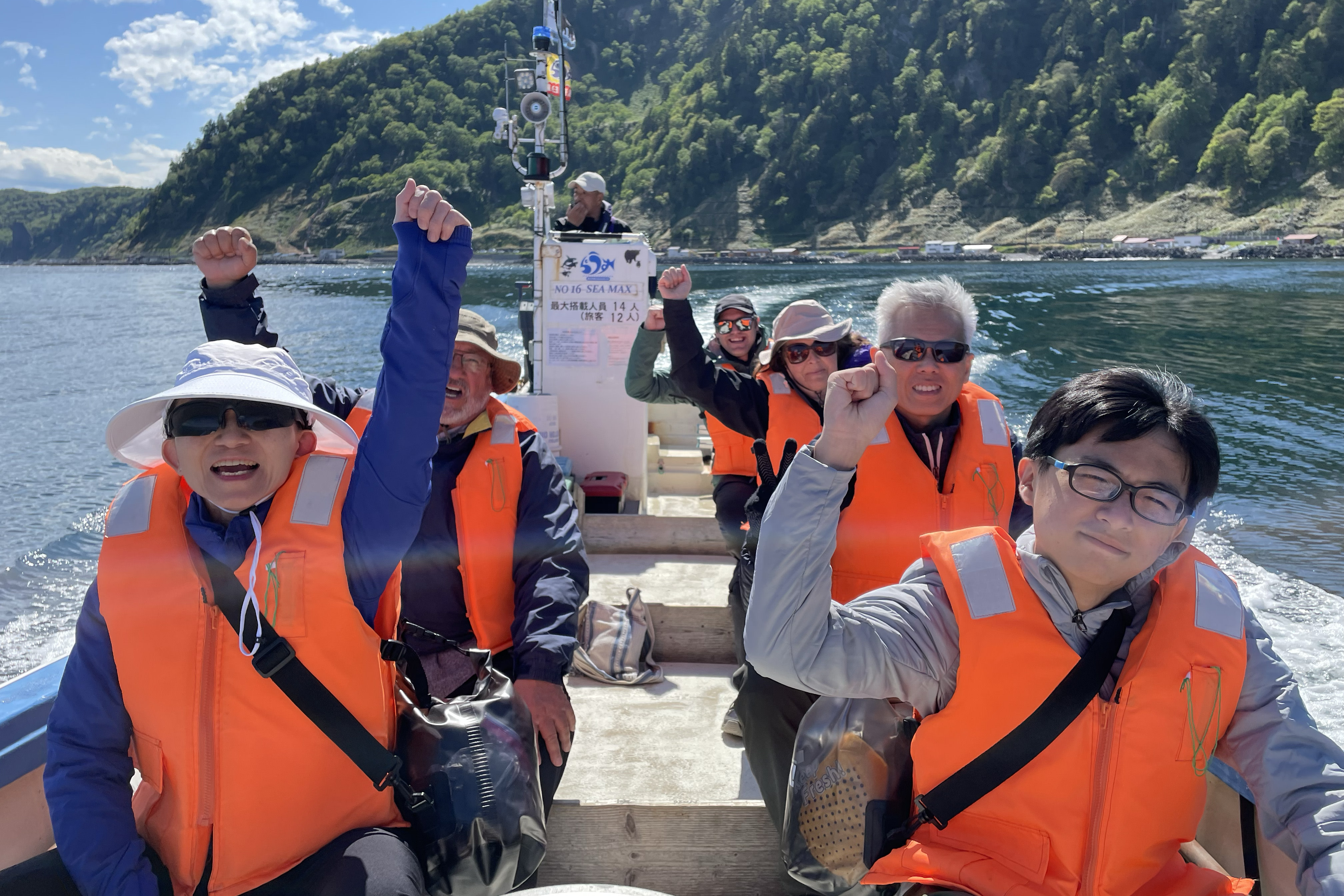 A group of tourists pump their fists aboard a small boat off the Shiretoko coast