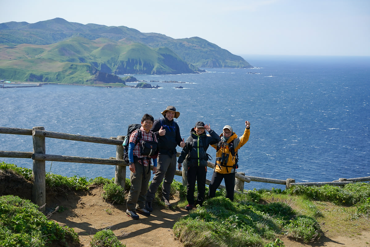 A group of hikers poses on a cliff top