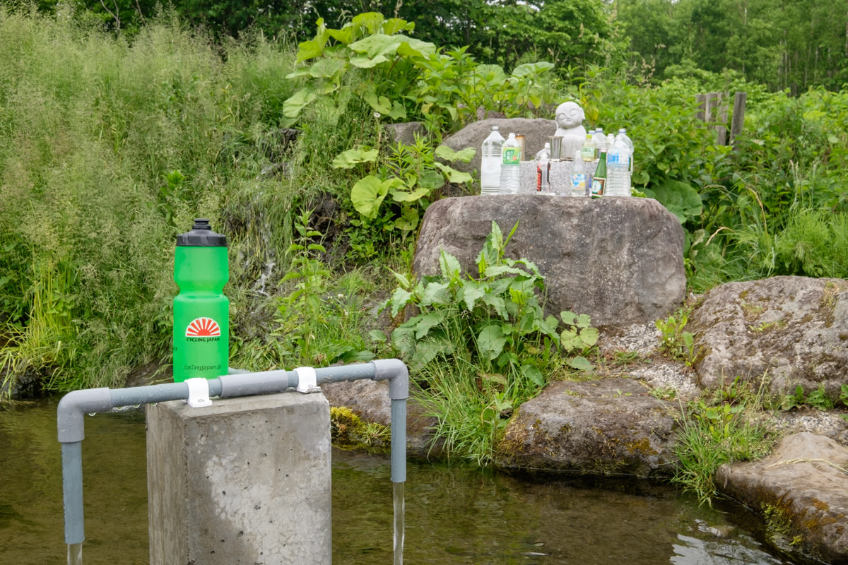 A cycle tourists water bottle sits on a natural spring in front of a shrine