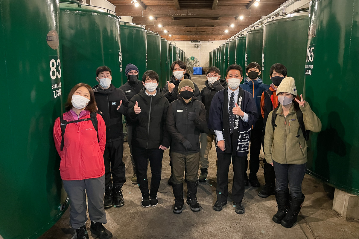 Group photo amongst gallons of sake rice wine.