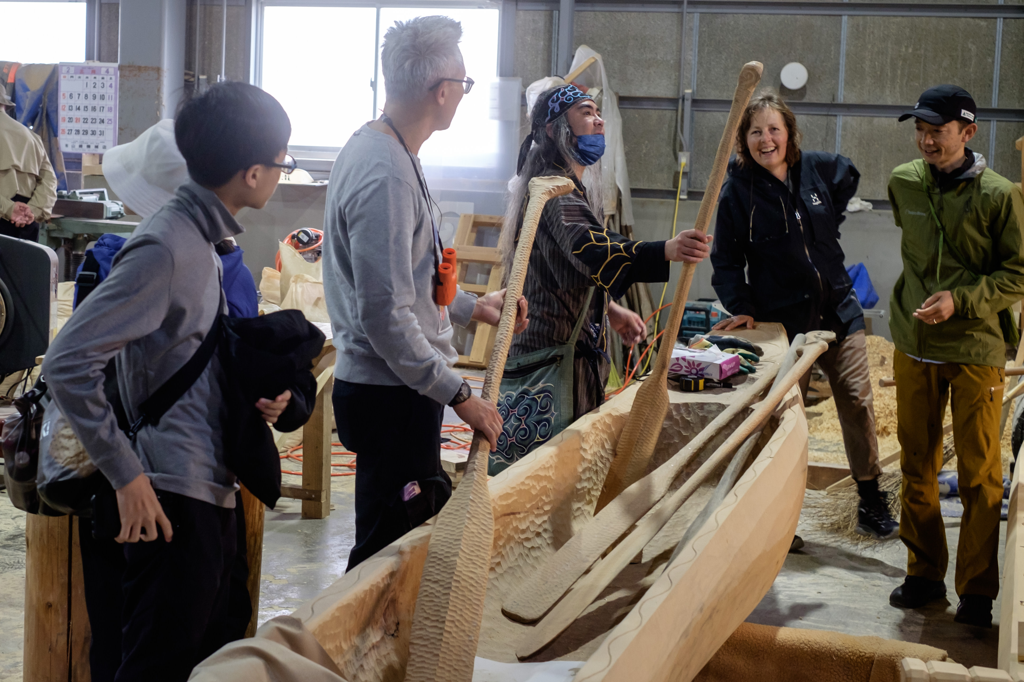 An Ainu guide shows a newly carved paddle that is part of a new dugout canoe he has built