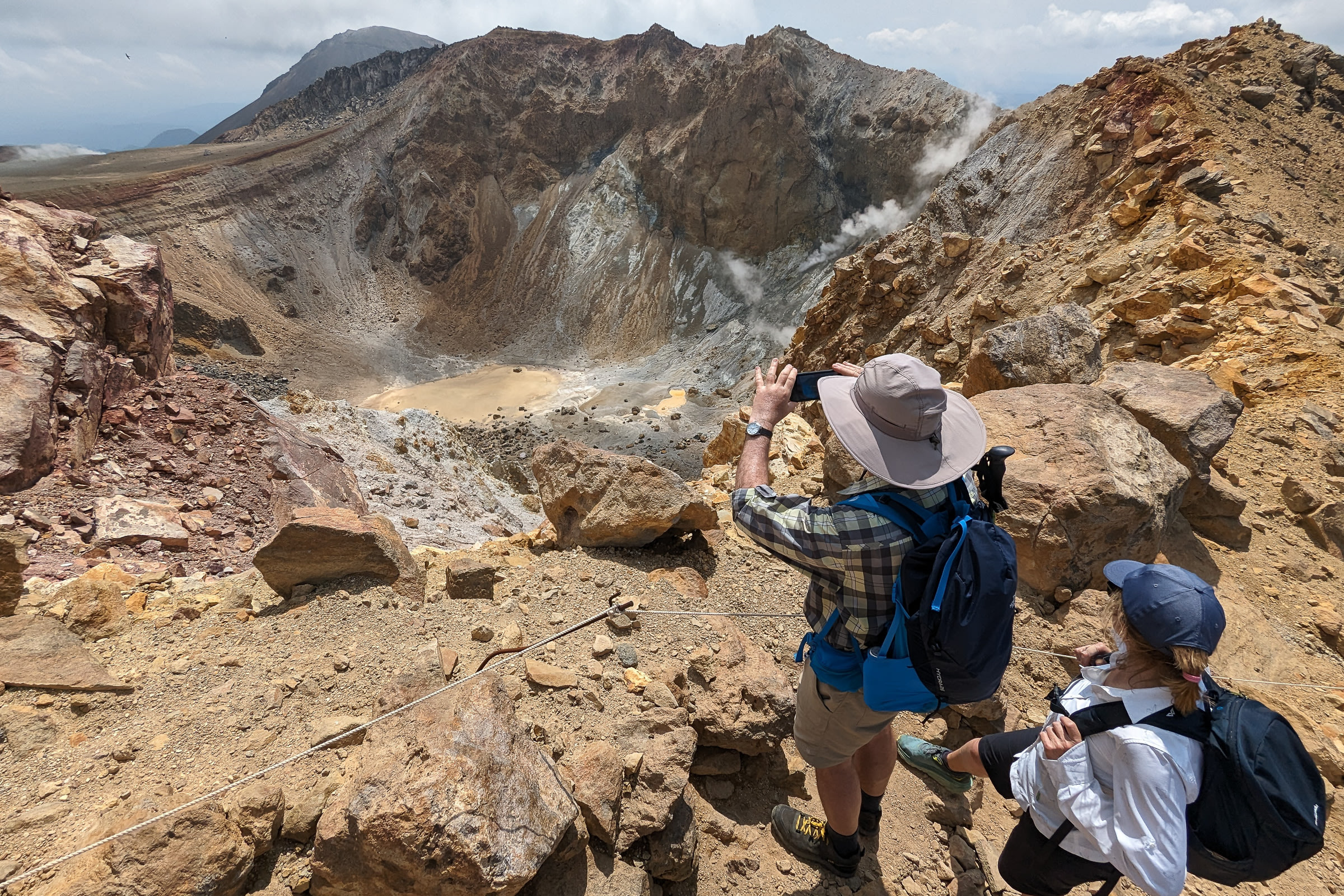Hikers take pictures of Mt Meakan's craters from up high.