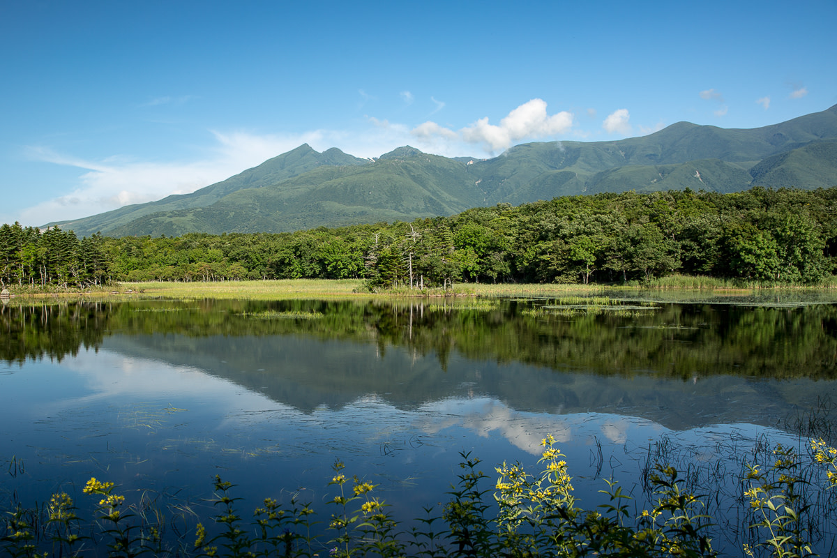 The mountains of the Shiretoko National Park are reflected in a still lake at Shiretoko Five Lakes