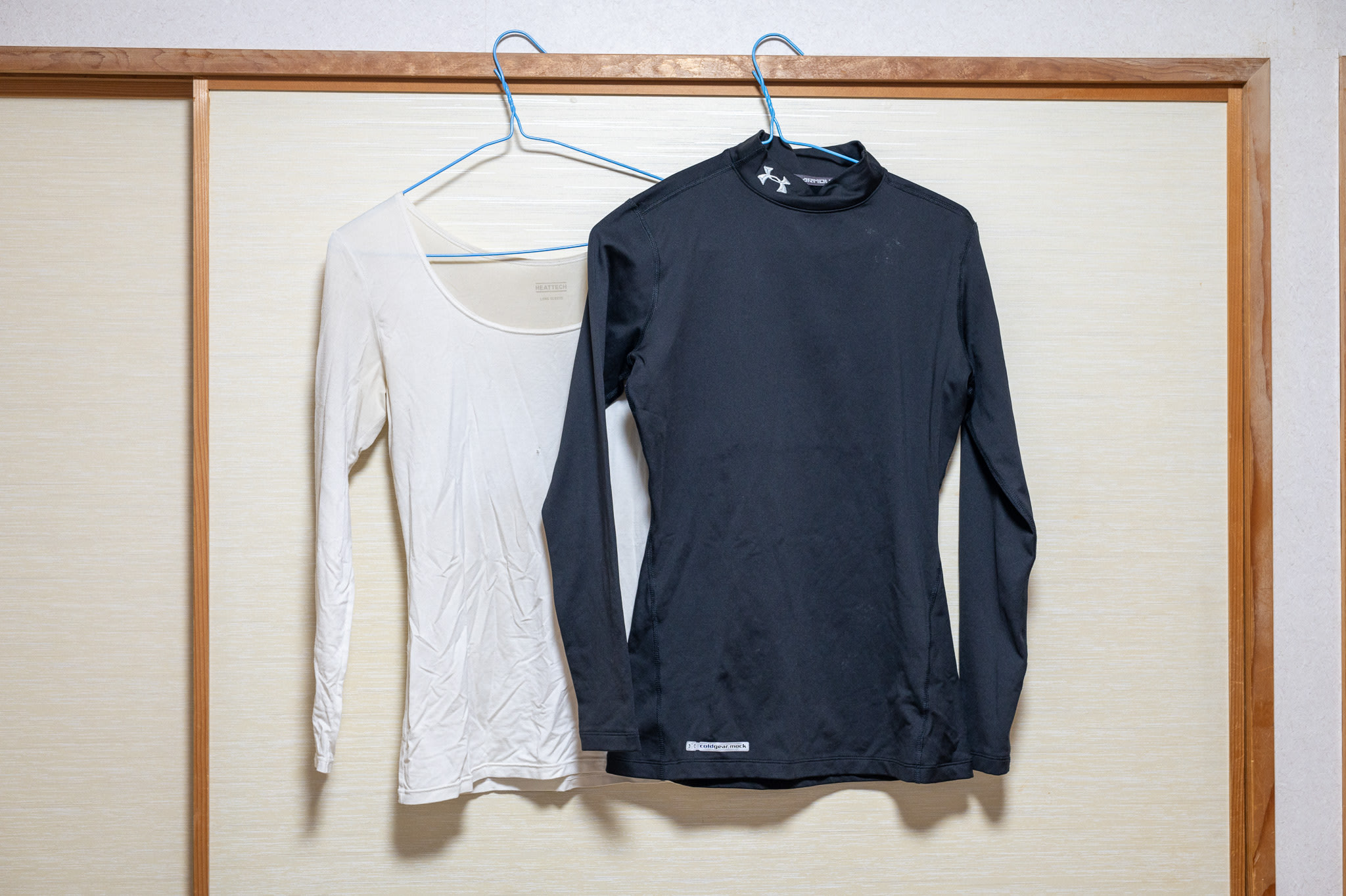Two thermal tops on hangers against a closet. One is high-necked, the other is a scoop-neck.