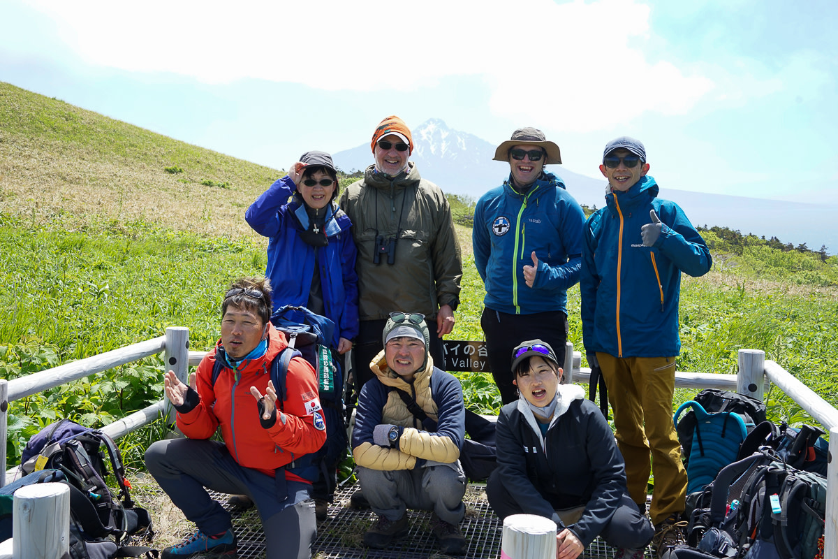 A group of hikers pose with Mt Rishiri in the background