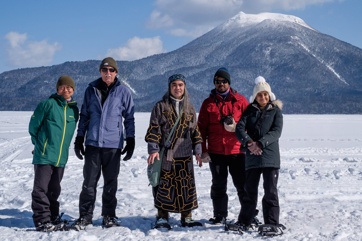 A group of tourists pose in front of Mt Oakan with their Ainu and Japanese guides