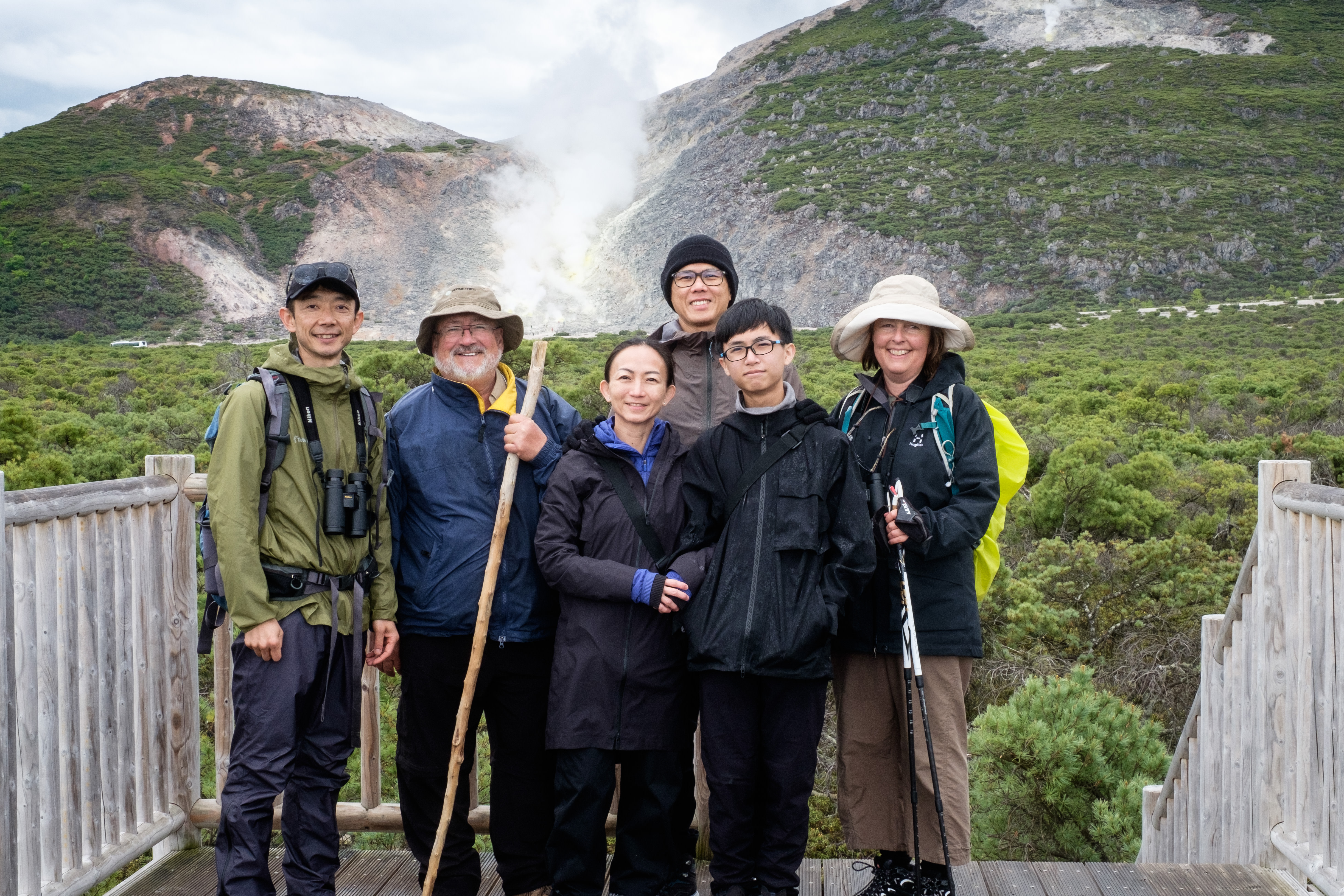 A group of walkers pose in front of Mt Io. In the background the sulphuric steam can be seen rising from an exposed patch of land.