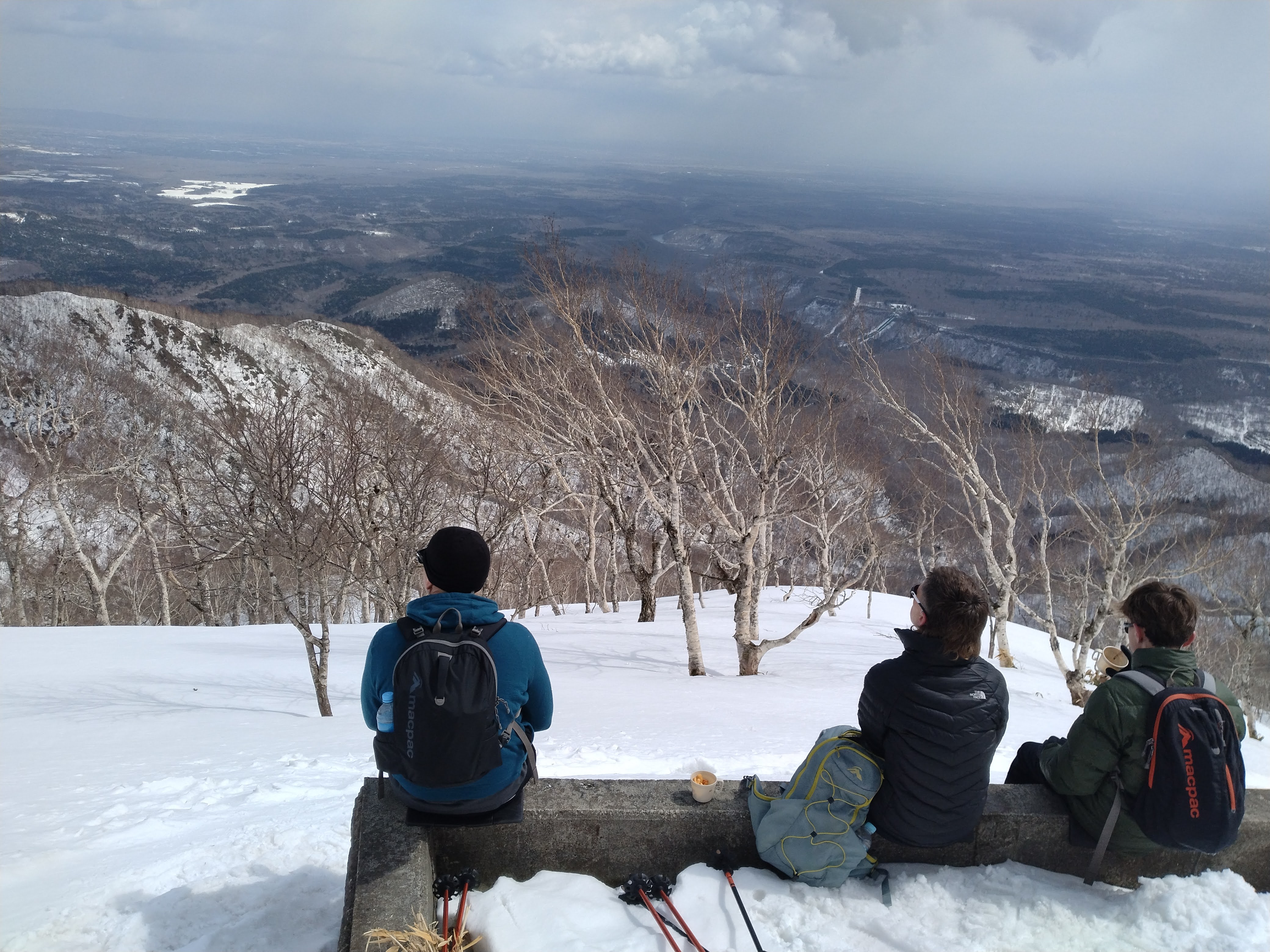 Three guests soak in the view from the top of Mt. Monbetsu while taking a quick break from snowshoeing.