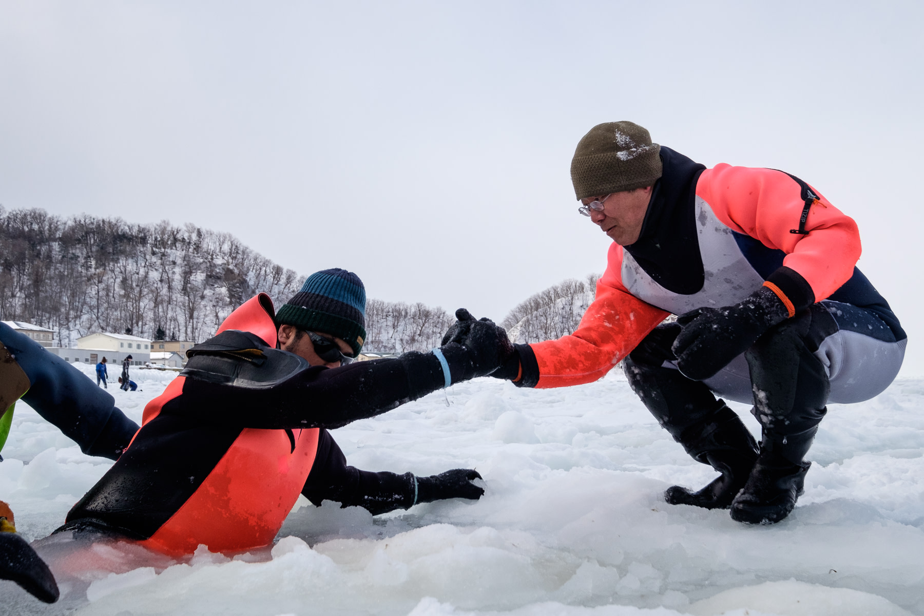 A guide helps a guest climb up onto the ice off the coast of Utoro in Shiretoko.