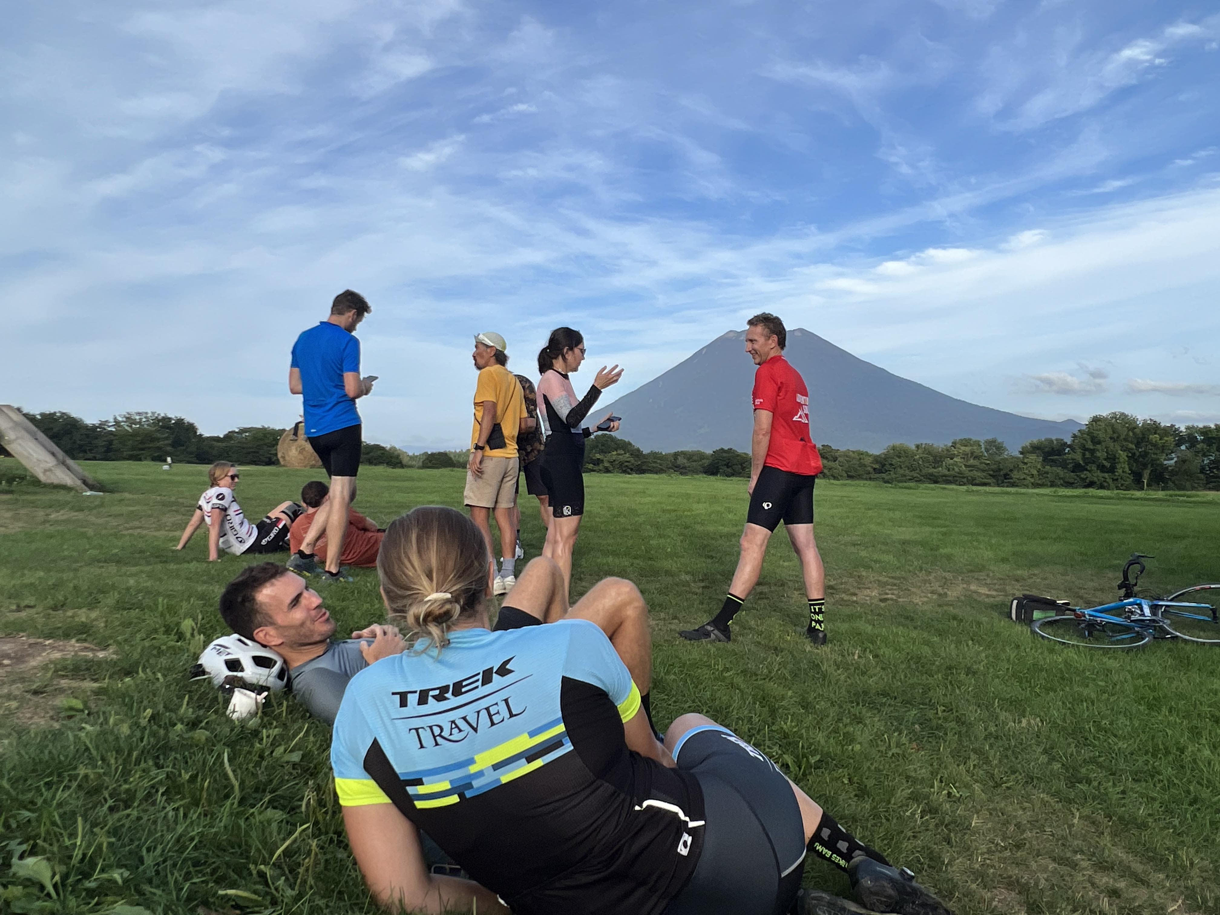A group of cyclists take a well-deserved break after a long day of cycling with Mt. Yotei in the distance.