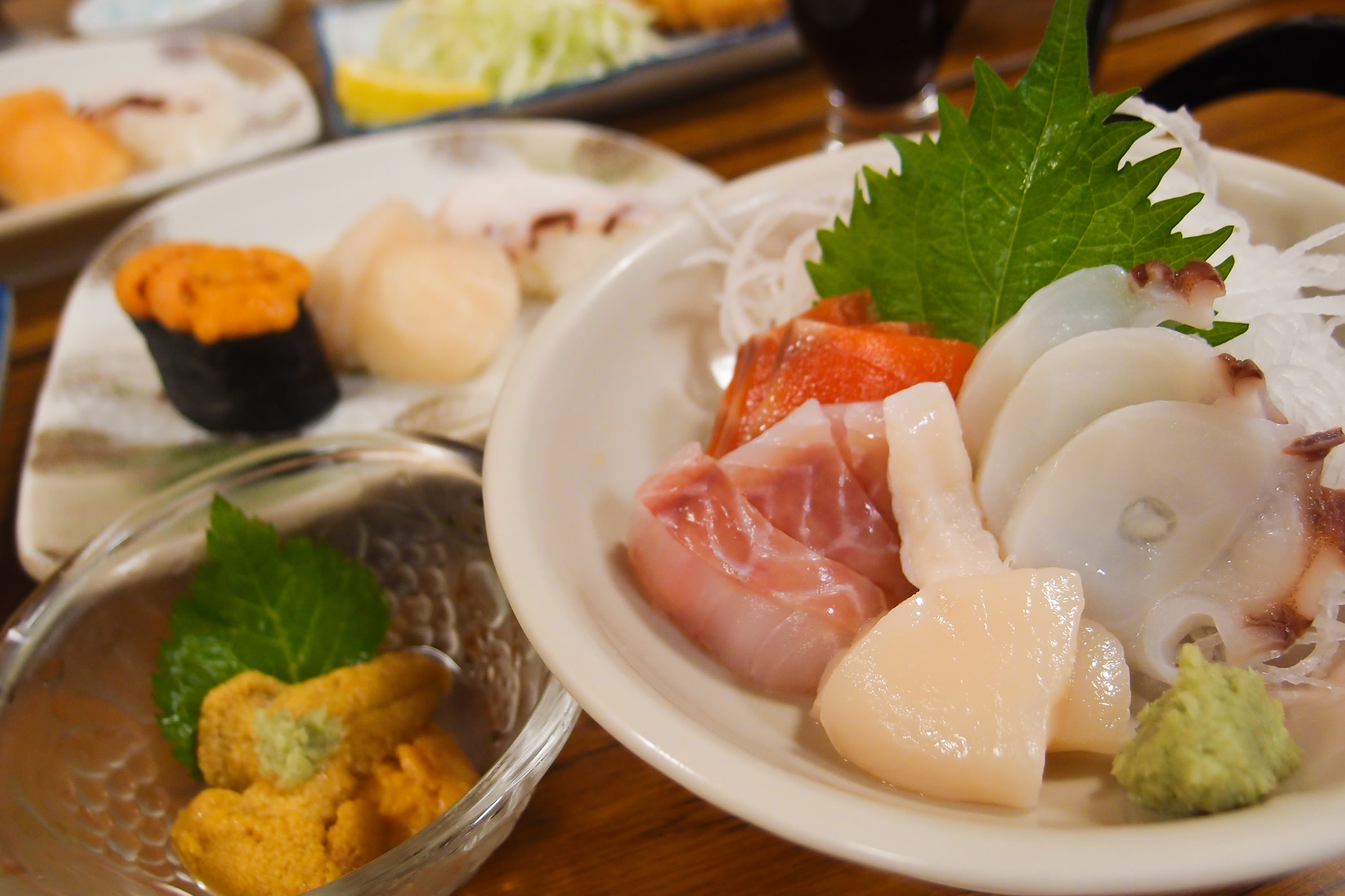 A plate of fresh sashimi, including scallops, sea bream, salmon, octopus and sea urchin.