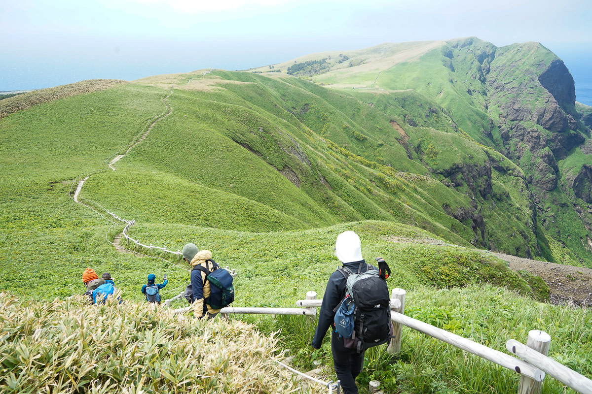 A group of hikers walks along the clifftop Momoiwa trail