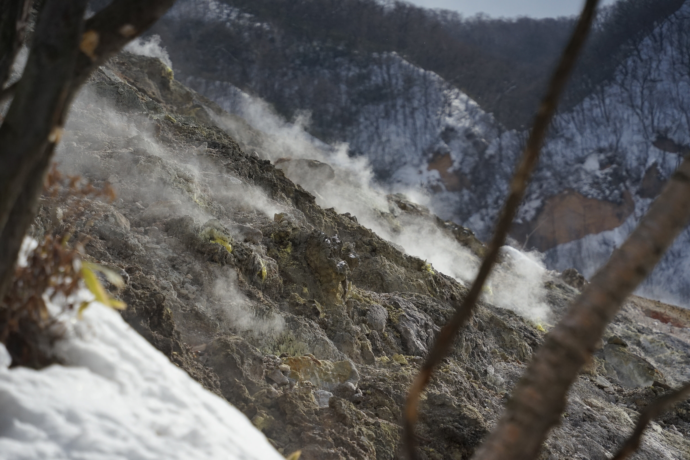 Bare rocks steaming at Noboribetsu Hell Valley in winter.