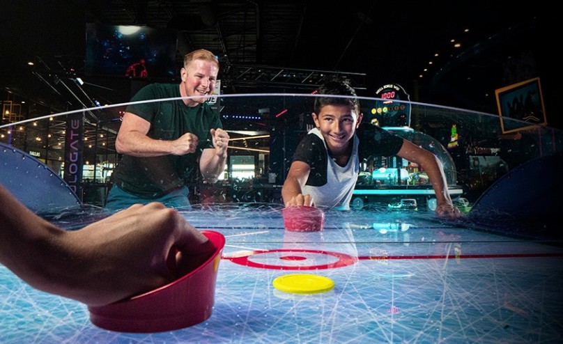 Family playing air hockey at Main Event’s interactive game room