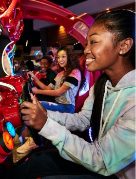 Teens playing driving arcade game