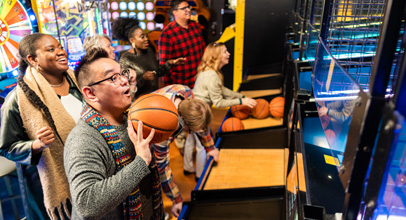 Man shooting basketball into arcade game