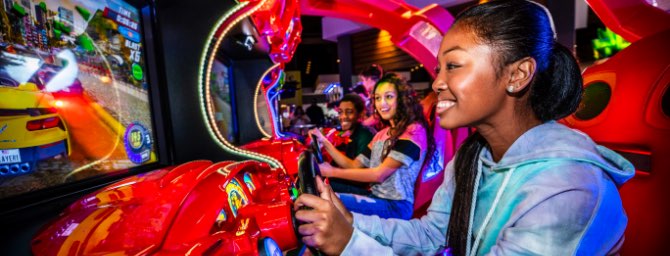 Teens playing driving arcade game