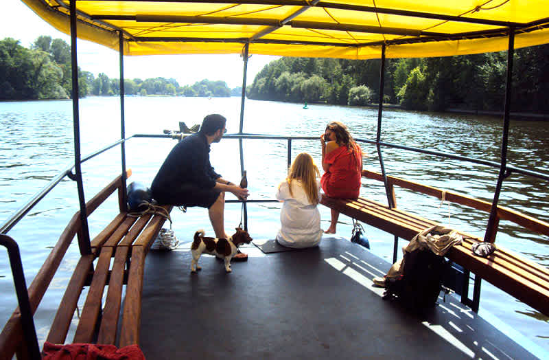 Bow of the Berlin party boat Hopper with wooden benches and three passengers