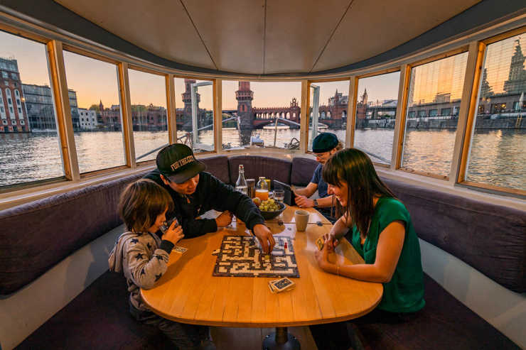Blick aus dem Wohnzimmer auf die Oberbaumbrücke und einer Familie beim spielen auf dem Hausboot Rossi