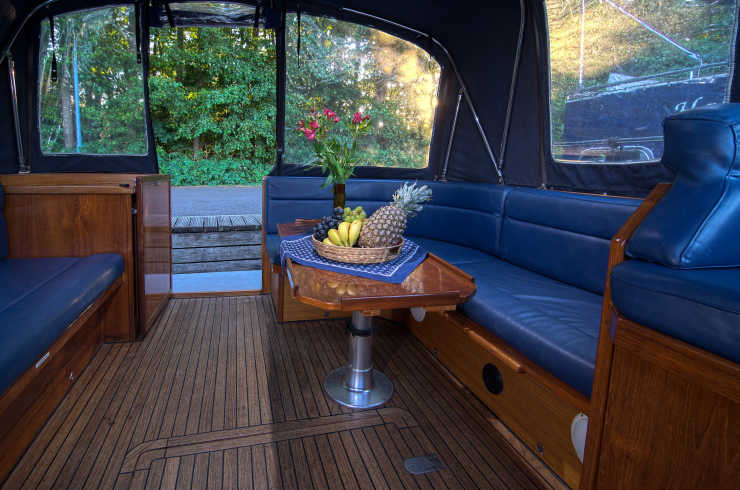 Hausboot Theresa Außenbereich in Holzoptik und mit blauer Sitzecke und Regendach