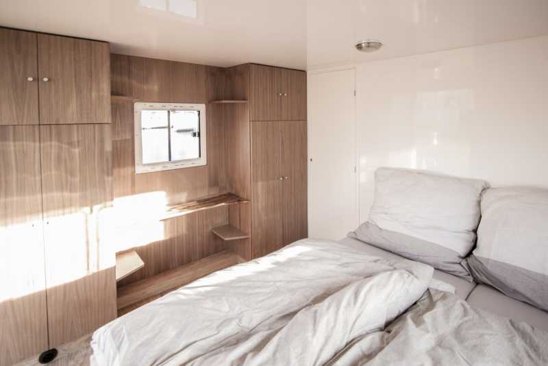 Gemütliches Schlafzimmer mit Holzschränken auf dem Hausboot Flexmobil von Berlin Bootsverleih