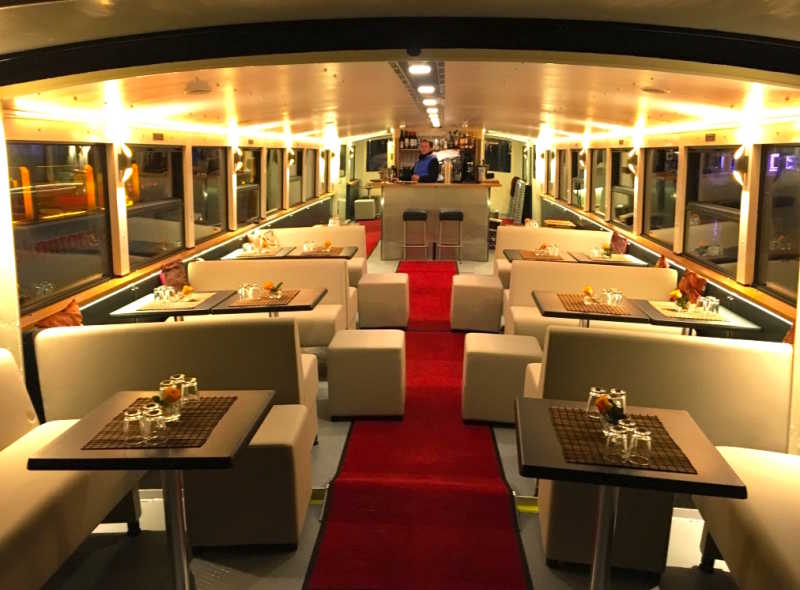 Salon with red carpet, tables and bar area on the Arcona ship 