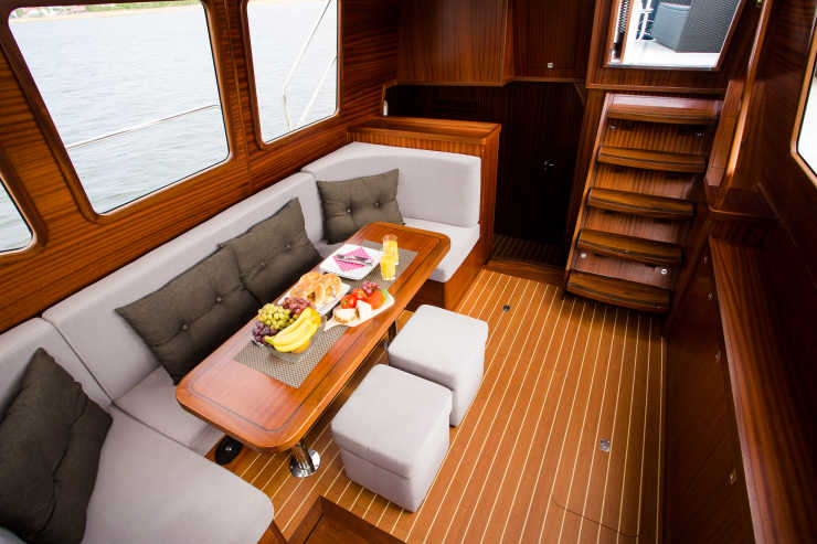Elegant salon in wood look with seating area and table on our houseboat Nautiner