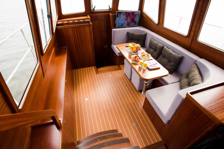 Edler Innenbereich aus Tropenholz mit blauer Sitzecke, Tisch und Catering auf dem Hausboot Nautiner