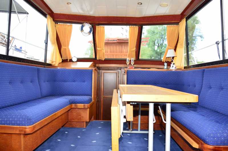 Salon mit blauer Sitzecke und Tisch auf dem Hausboot Maxima