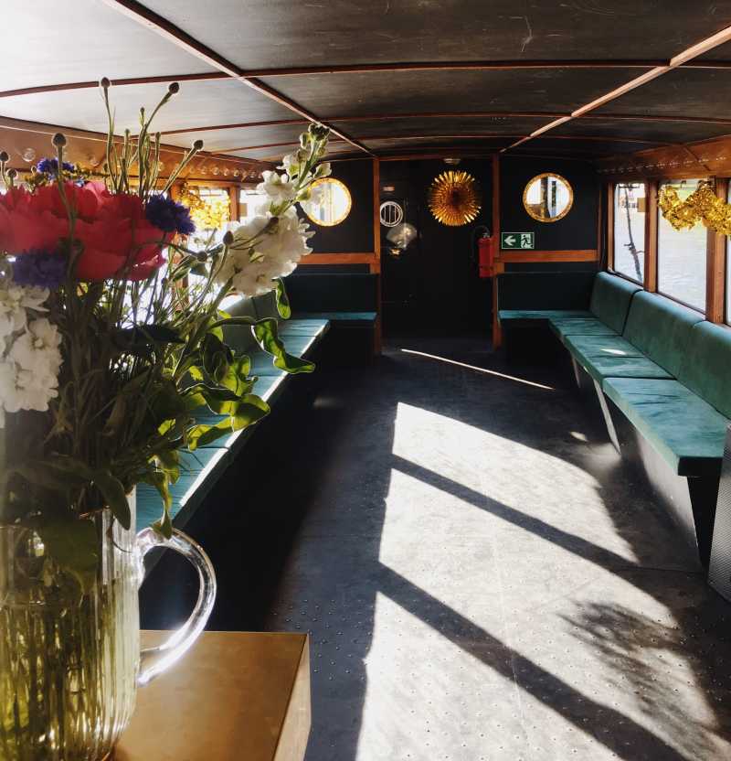 Eleganter Salon des Schiffes Golda mit grünen Sitzen und Blumen