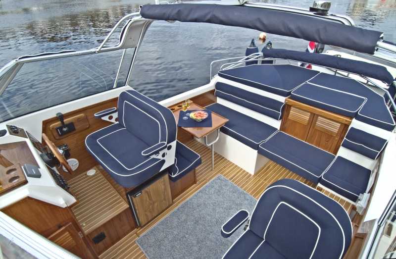 Cockpit and outside area with blue seat cushions and wooden deck on the houseboat Moin