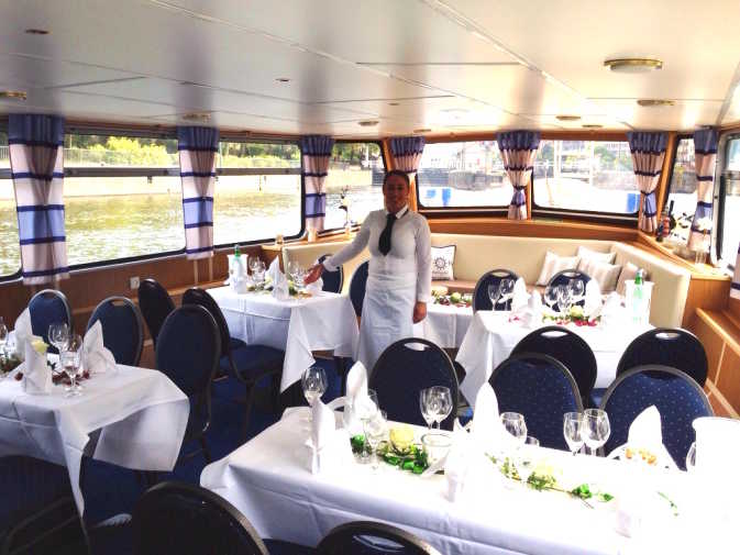 Lower deck with laid tables and service personnel on the Bon Ami ship