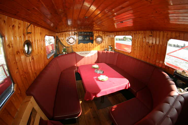 Salon aus Holz mit Sitzecke aus rotem Leder an Bord des Schiffes Country Star