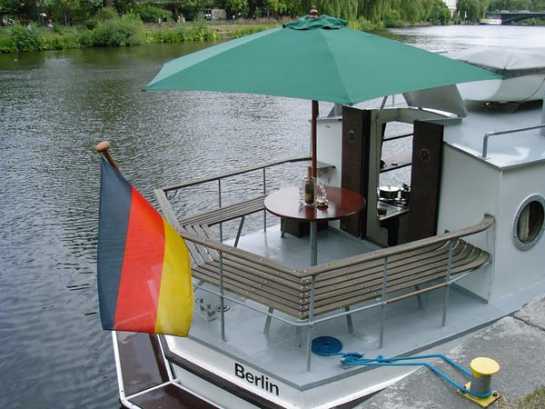 Außenbereich mit Sitzecke und Sonnenschirm am Heck des Charterschiffes MS Heidelberg