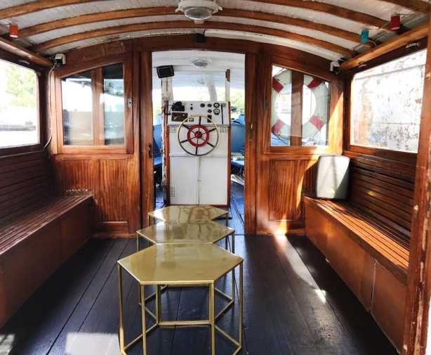 Salon of the boat Mieze with beautiful wooden benches, wooden walls and golden tables